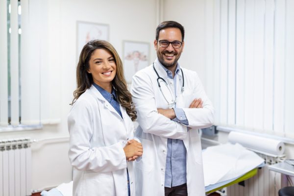 Portrait of smiling young doctors standing together. Portrait Of Medical Staff Inside Modern Hospital Smiling To Camera Smiling doctors discussing accounting